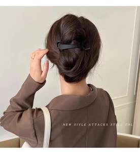 Close-up of matte black hair clip styled in a low ponytail on brunette hair