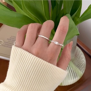 Close-up of minimalist twist ring and chain ring with tiny gems on female fingers