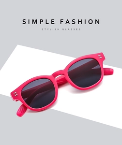 Close-up of pink round sunglasses frame featuring silver rivet detail and dark lenses