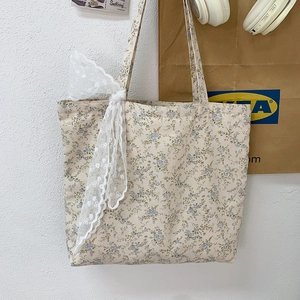 Detailed shot of floral canvas tote bag featuring delicate blue flowers and lace bow