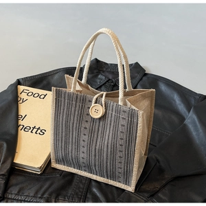 Detailed texture of striped linen tote bag featuring wooden button and rope handles