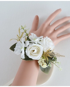 Detailed view of an elegant white artificial rose wrist corsage with lush green leaves