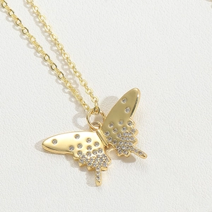 Macro shot of gold butterfly pendant with sparkling cubic zirconia on white leather texture