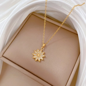 Macro detail of gold daisy pendant with pavé crystals in a beige velvet jewelry box