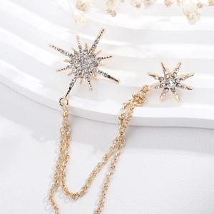 Detailed view of golden starburst brooch with double chains and inlaid rhinestones