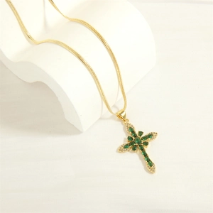 Macro shot of gold cross necklace with green zircon stones on snake chain in elegant scene