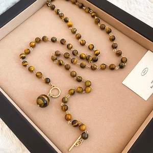 Dettaglio macro della collana di perle occhio di tigre con ciondolo tondo in confezione