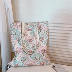 Close-up of floral canvas tote bag with white woven label and reinforced shoulder strap