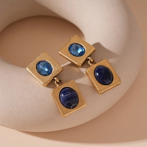 Macro shot of vintage gold earrings with light and dark blue gemstone insets