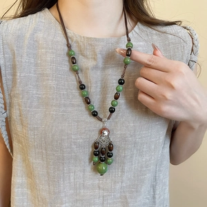 Detailed view of handmade ethnic beaded necklace with tassels on a neutral background