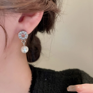 Close-up of silver drop earrings with sparkling rhinestones and elegant white pearls
