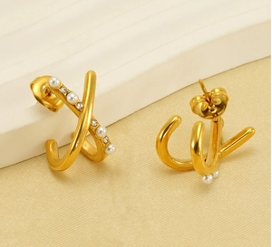 Detail of gold-plated cross-over earrings featuring pearls and sparkling rhinestones