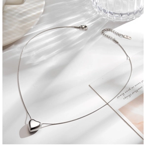 Detailed view of silver heart pendant with polished finish on a sleek snake chain necklace
