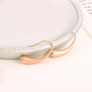 Elegant rose gold water drop earrings in irregular geometric design on a white ceramic plate