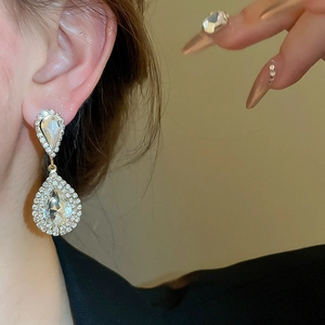 Detail of luxury water drop earrings with shiny rhinestones on female model