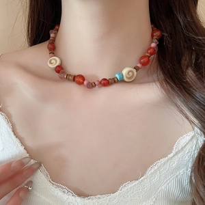 Detail of beaded necklace with red agate, wood beads and turquoise on white lace collar
