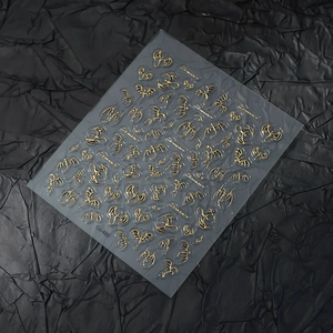 Macro shot of gold dragon nail stickers with embossed textures on a black background