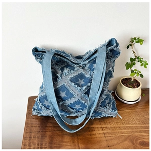 Detail of blue denim tote bag featuring star patchwork with vintage distressed frayed edges