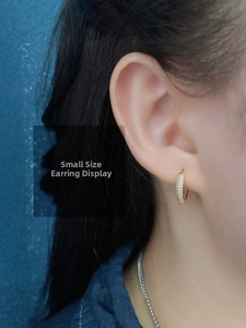 Close-up of small gold sterling silver hoop earring with cubic zirconia on a model ear