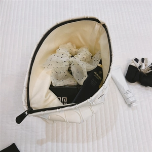 Detailed macro view of white textured canvas cosmetic bag with black zipper and beige lining