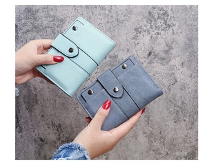 Close-up of mint green and grey leather wallets showing fine stitching and metal studs