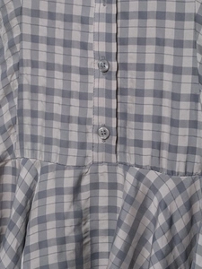 Detail of grey gingham fabric texture with matte buttons and pleated waist design
