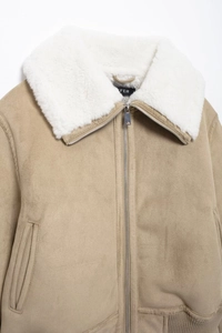 Gros plan du col en fausse fourrure blanche et du zip de cette veste aviateur en daim