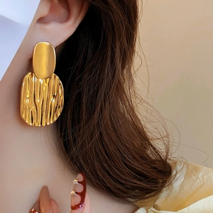Vue détaillée des boucles d'oreilles dorées à texture de lave sur un mannequin