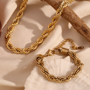 Macro shot of 18K gold plated rope chain jewelry set on champagne silk and coral