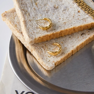 Detail of 18K gold-plated stainless steel C-hoop earrings with irregular hammered texture