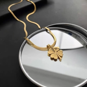 Golden four-leaf clover pendant on a sleek snake chain necklace reflected on a mirror