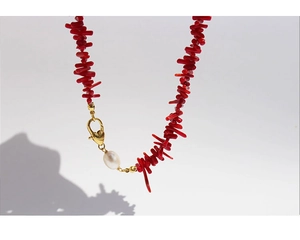 Detail of red branch beads necklace with white baroque pearl and golden heart clasp