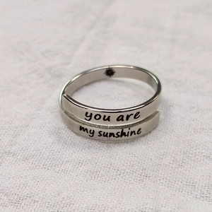 Close-up of engraved 'you are my sunshine' text on silver wrap ring band
