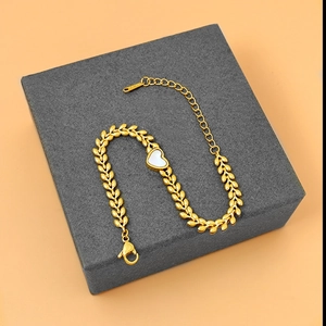 Detailed macro of 18K gold plated steel bracelet with white shell heart on jewelry box