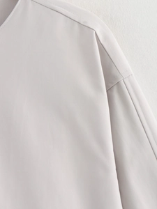 Close-up of light gray flight jacket shoulder featuring clean seams and fine fabric texture