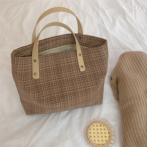 Detail of vintage brown plaid tote with white leather handle and gold rivet accents