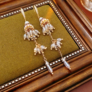 Détail de boucles d'oreilles bohèmes vintage avec perles dorées et cristaux sur tissu olive