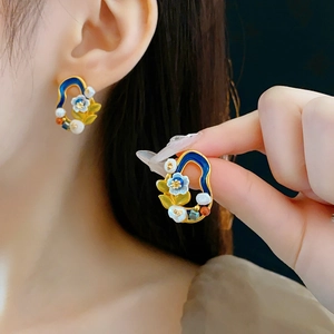 Detail of vintage flower earrings with freshwater pearls and gold enamel finish