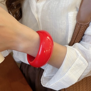 Close-up of a bold red resin geometric round bangle bracelet worn by a model
