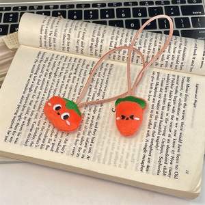 Detail of two cute carrot-shaped plush hair ties on an open book, soft embroidery texture