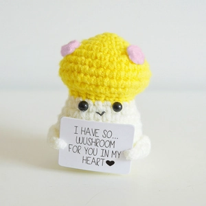 Detail of handmade crochet mushroom doll with polka dot cap holding a positive message card