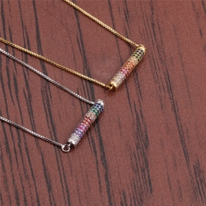 Gold and silver curved tube necklaces with colorful rainbow cubic zirconia on wood background