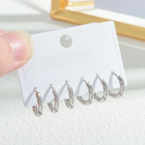 Detail of silver twisted metal earrings set with clear zircon stones on display card