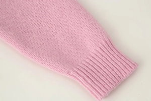 Close-up of a pink knitted cardigan showing detailed ribbed cuff texture and soft fabric