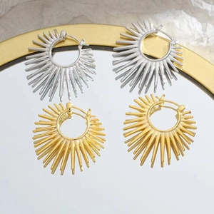 Minimalist sunflower earrings in gold and silver finish on a luxury mirror surface