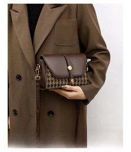 Detailed view of houndstooth canvas stitching and golden metal buckle on a brown bag