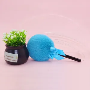 Detailed view of a soft blue plush powder puff with a bow and long black handle