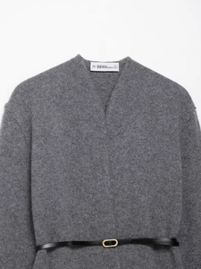 Detail of grey V-neck knit coat with black leather belt and gold buckle and brand label