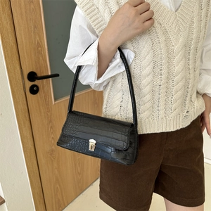 Borsa a spalla nera con trama a coccodrillo e fibbia dorata indossata dalla modella