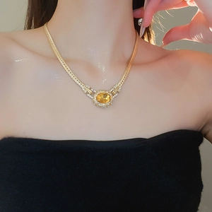 Close-up of vintage gold necklace featuring an oval amber gemstone and white rhinestones